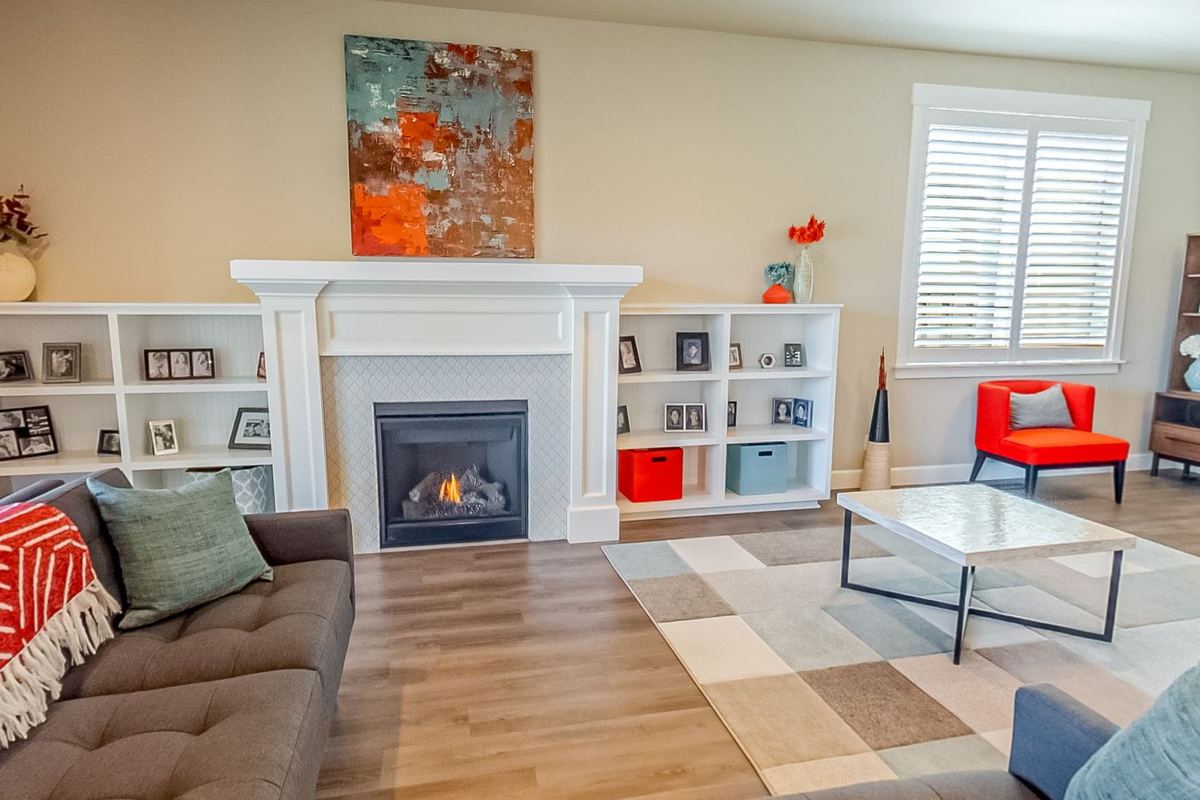 A family living room with a white fireplace, built in shelving and a corner sofa