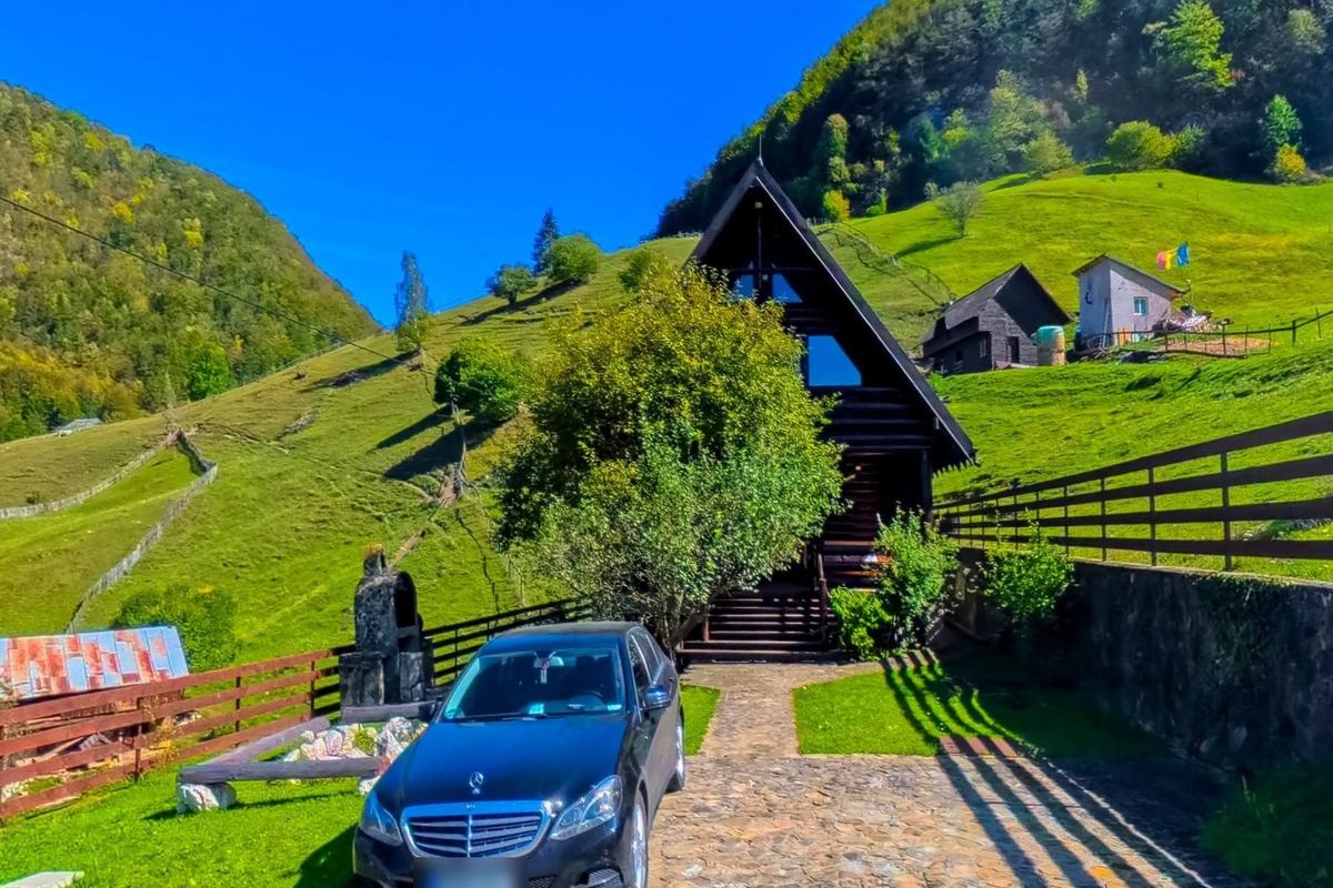 The dark timber Hunter's Lodge on a green slope above Dambovicioara
