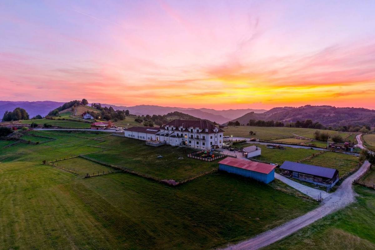 Magura Jina hotel on a green ridge above the village at sunset
