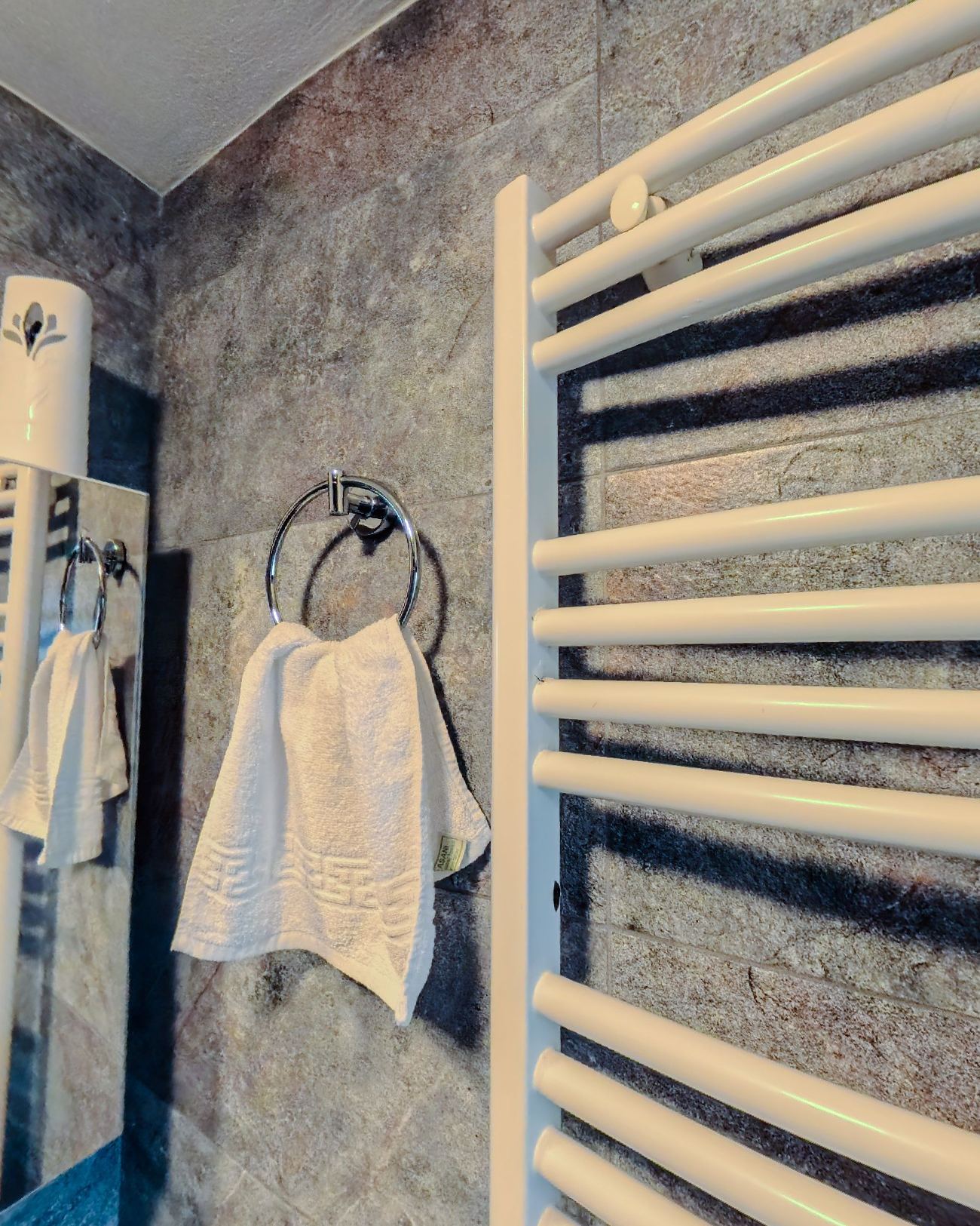 The bathroom in dark stone with a heated towel rail and white robes