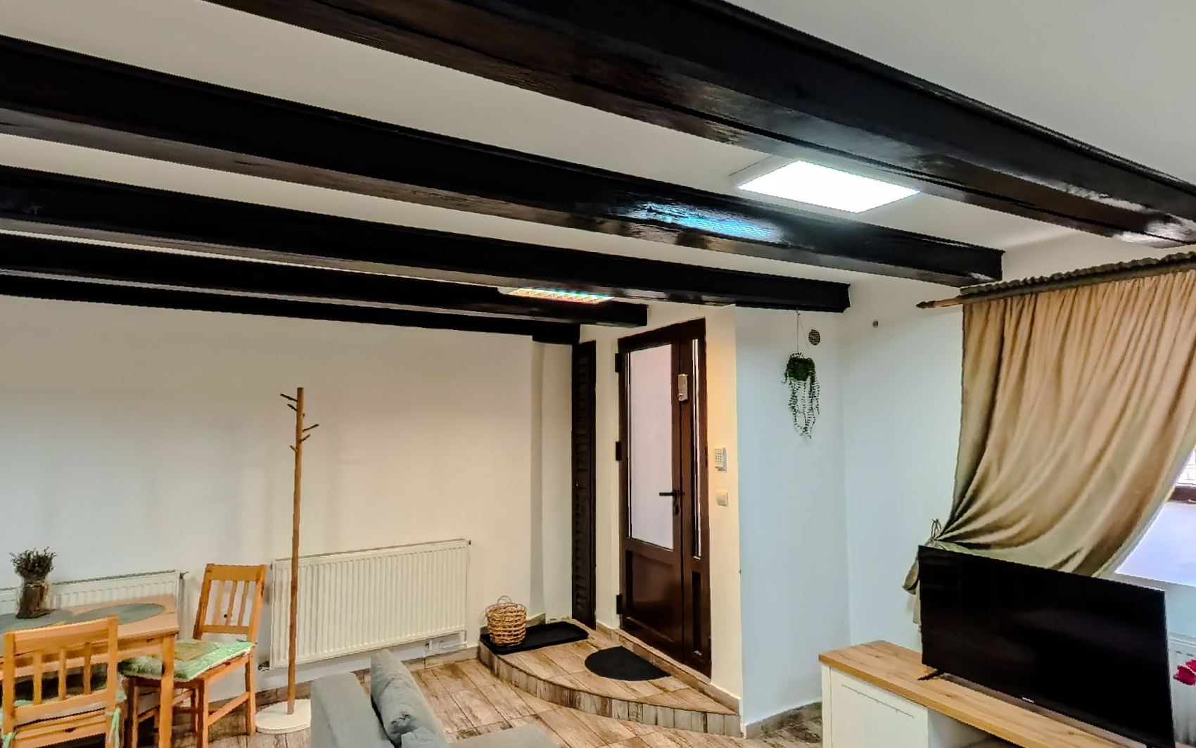 A wooden dining table and chairs under the beams