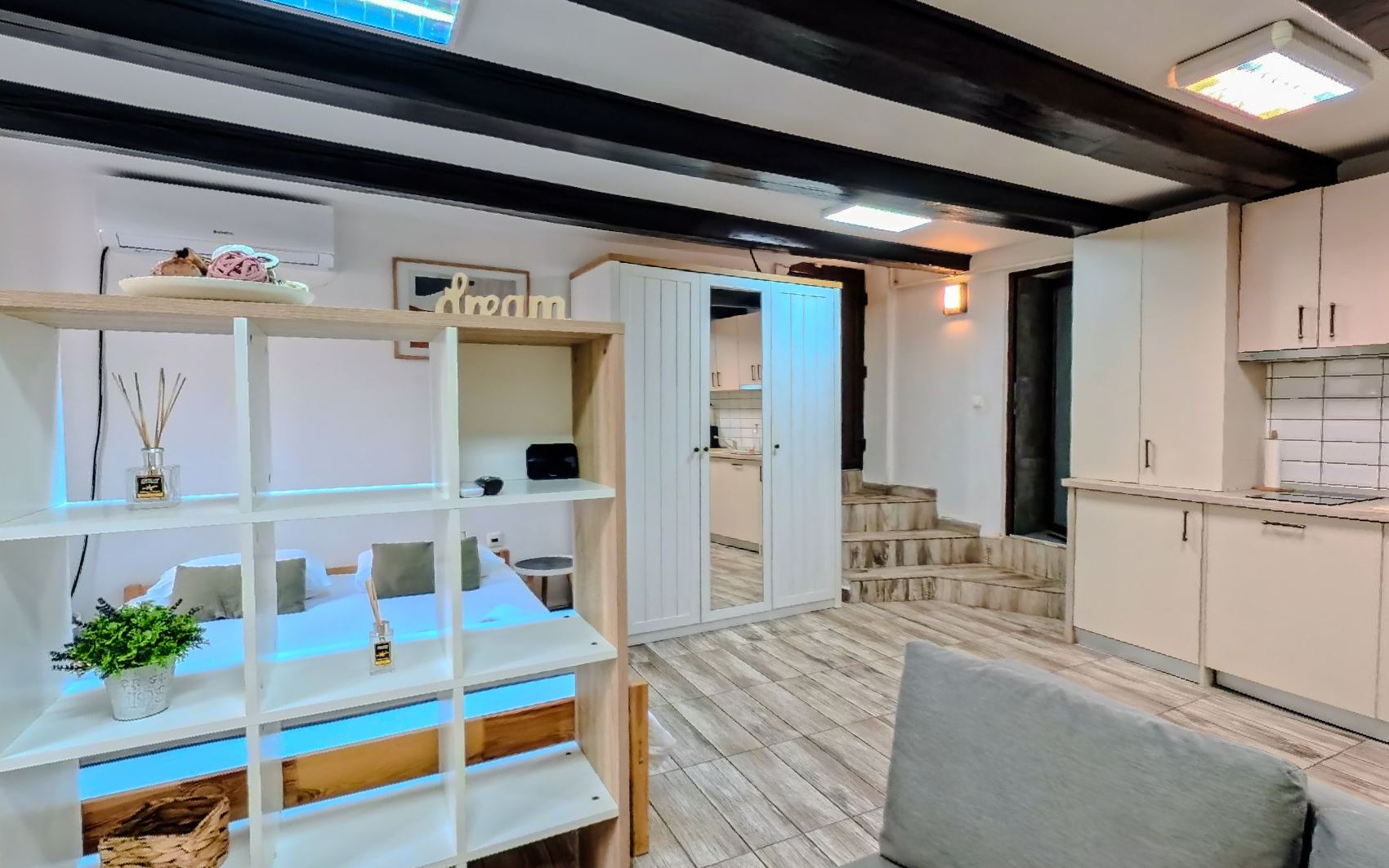The long room, white shelving and a sofa with the floor running down to the kitchen