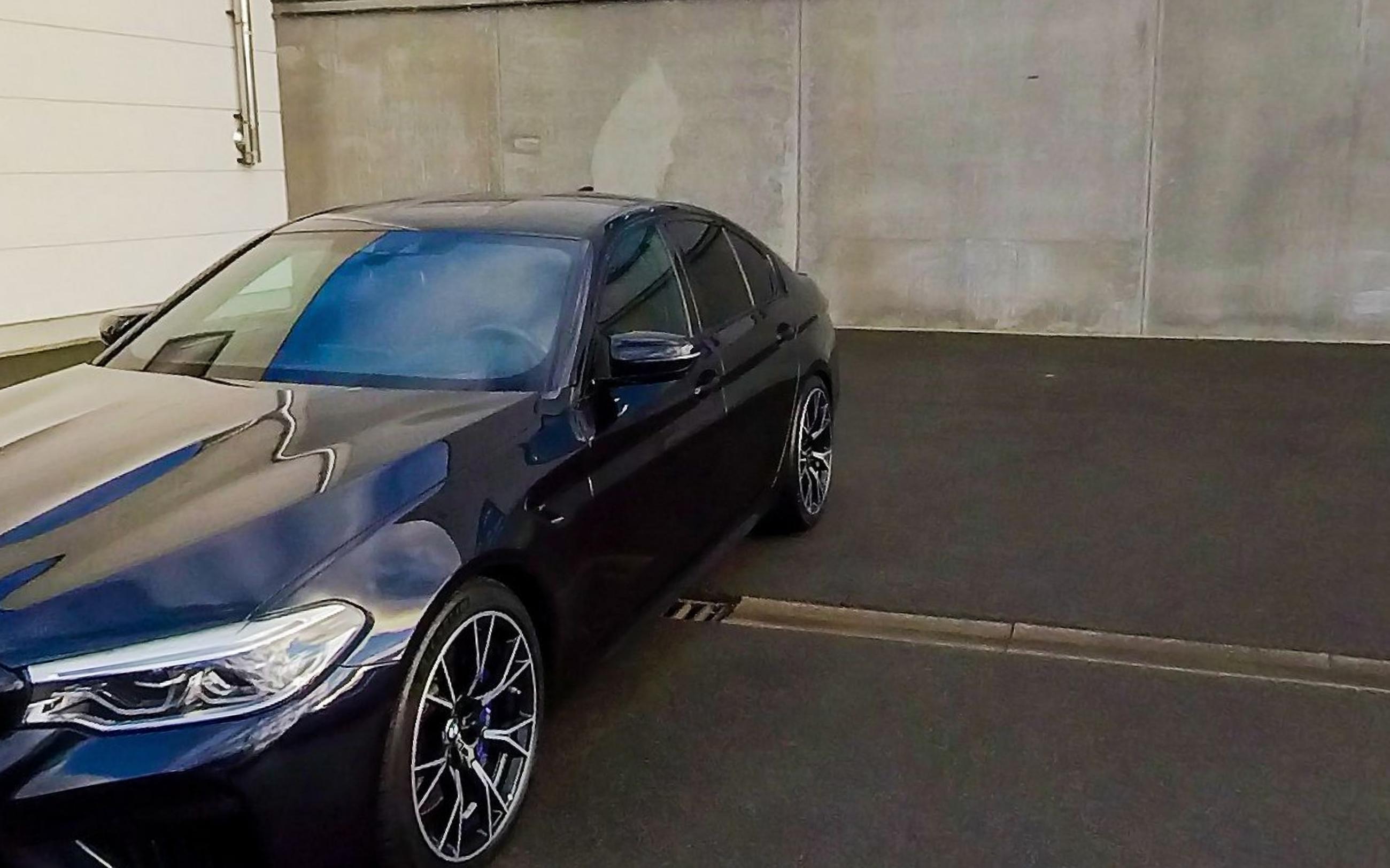 A black BMW M5 photographed from the front quarter on a dealer forecourt