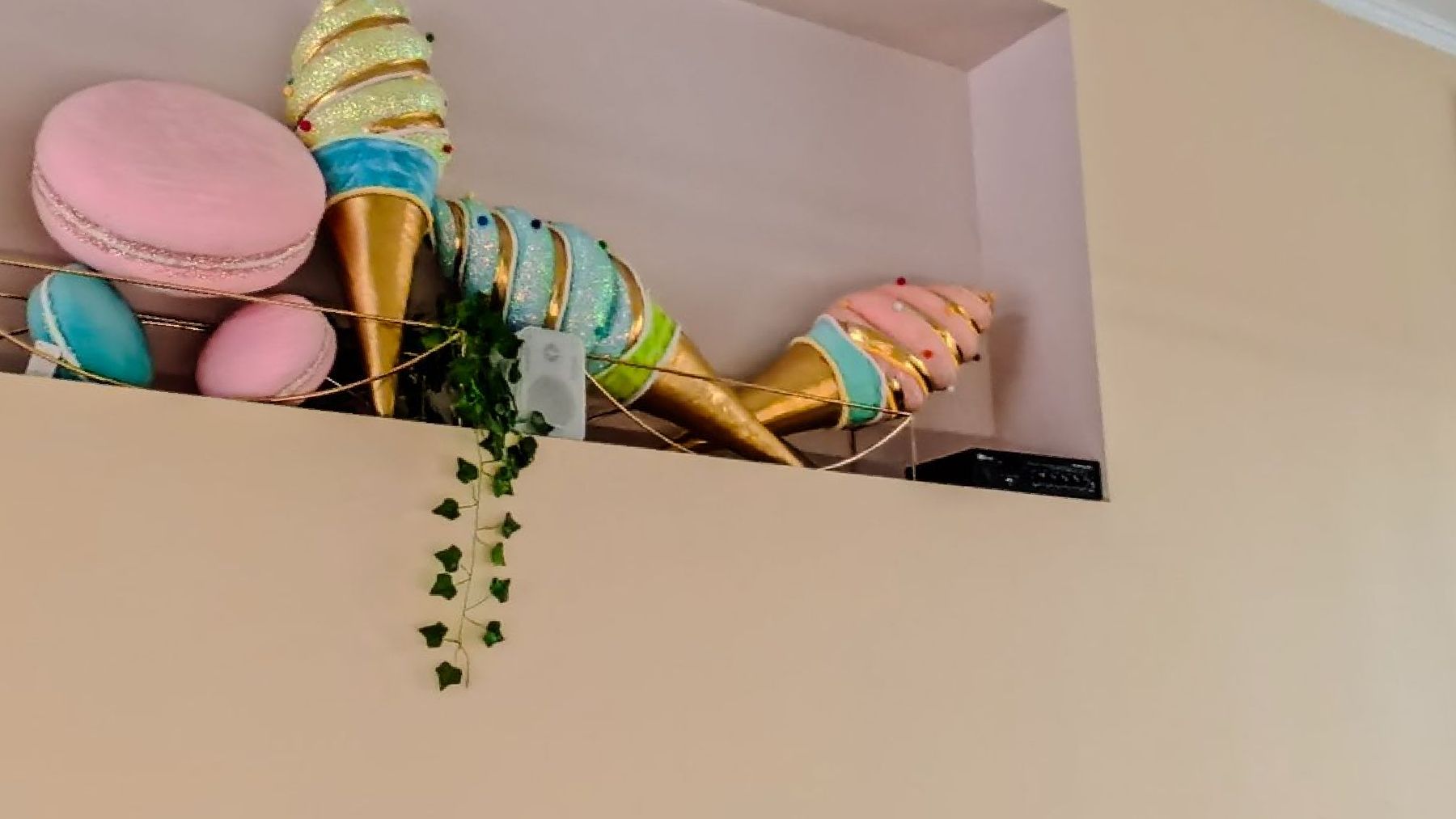 Oversized pastel cones and macarons on a shelf above the counter