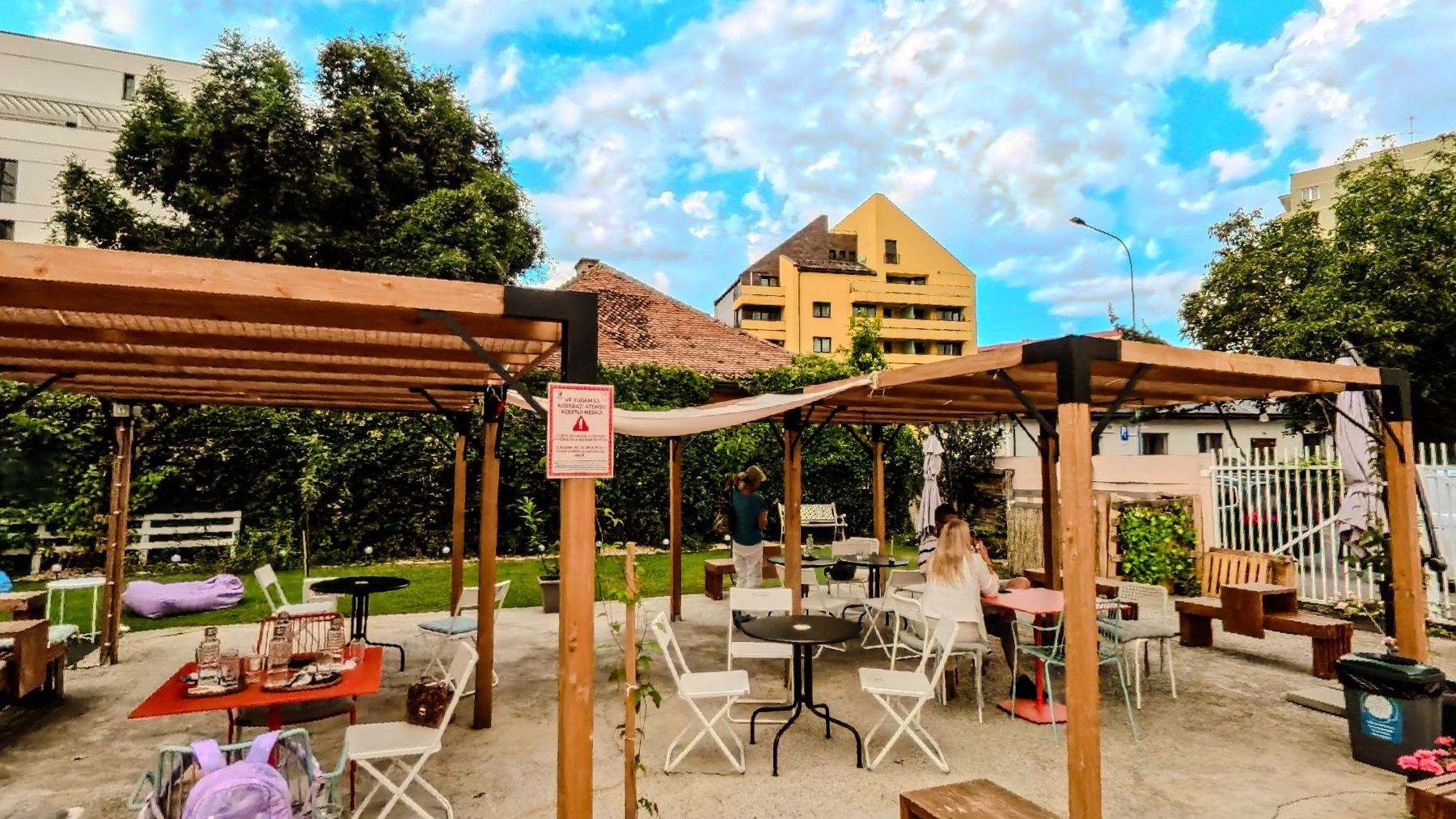 A wooden pergola over tables and chairs on the terrace