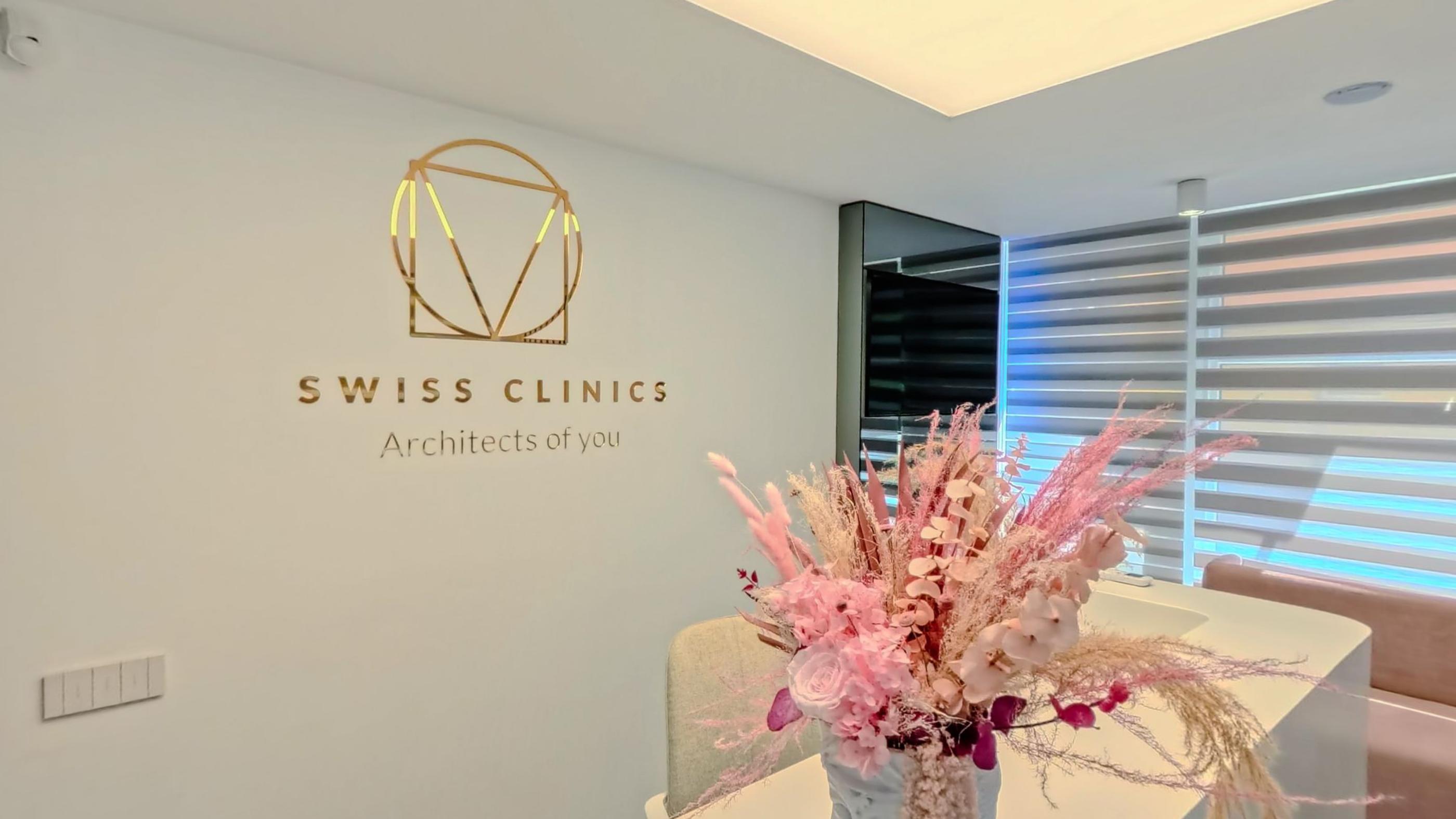 The reception wall with the gold wordmark and a tall arrangement of dried pink flowers