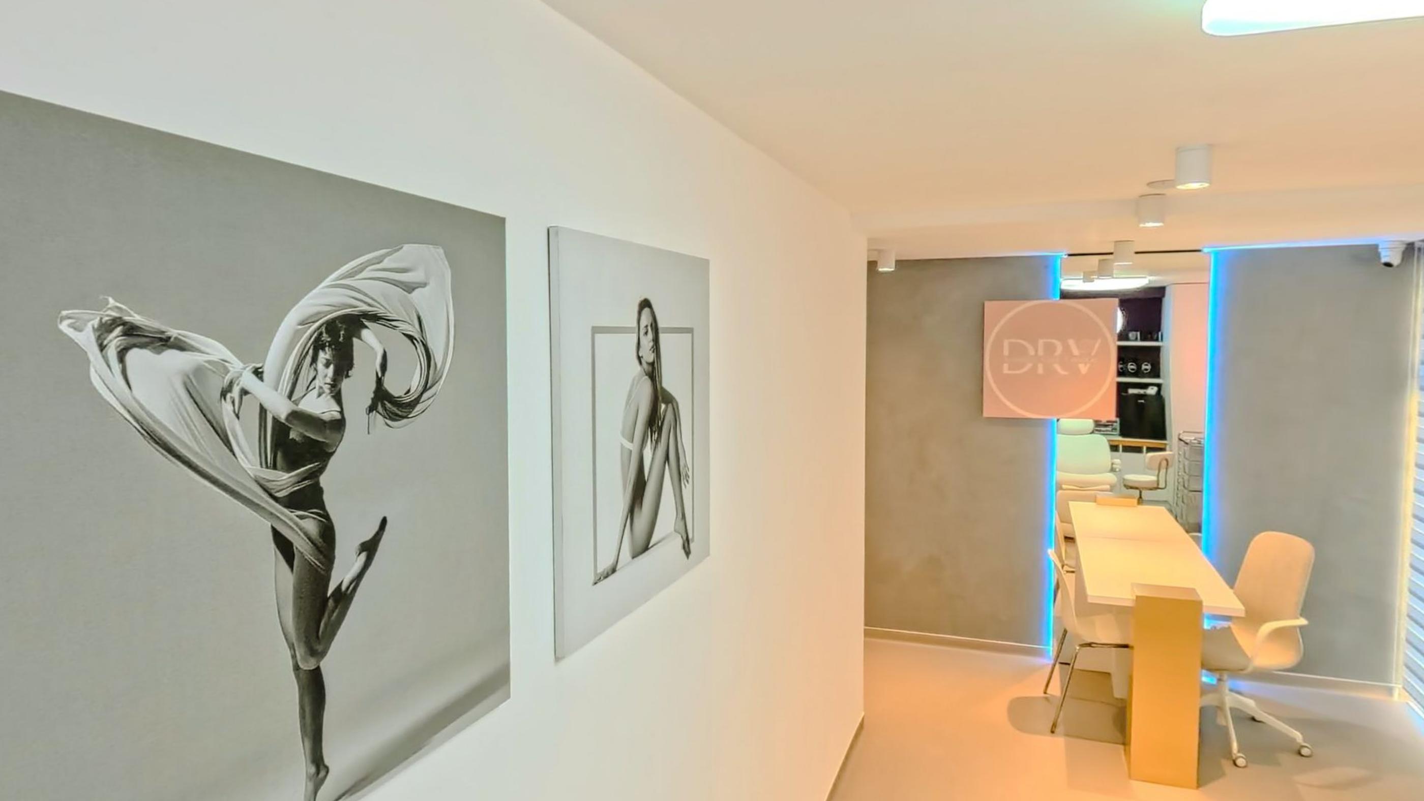 Two framed drawings of dancers on a long white wall, with daylight at the far end