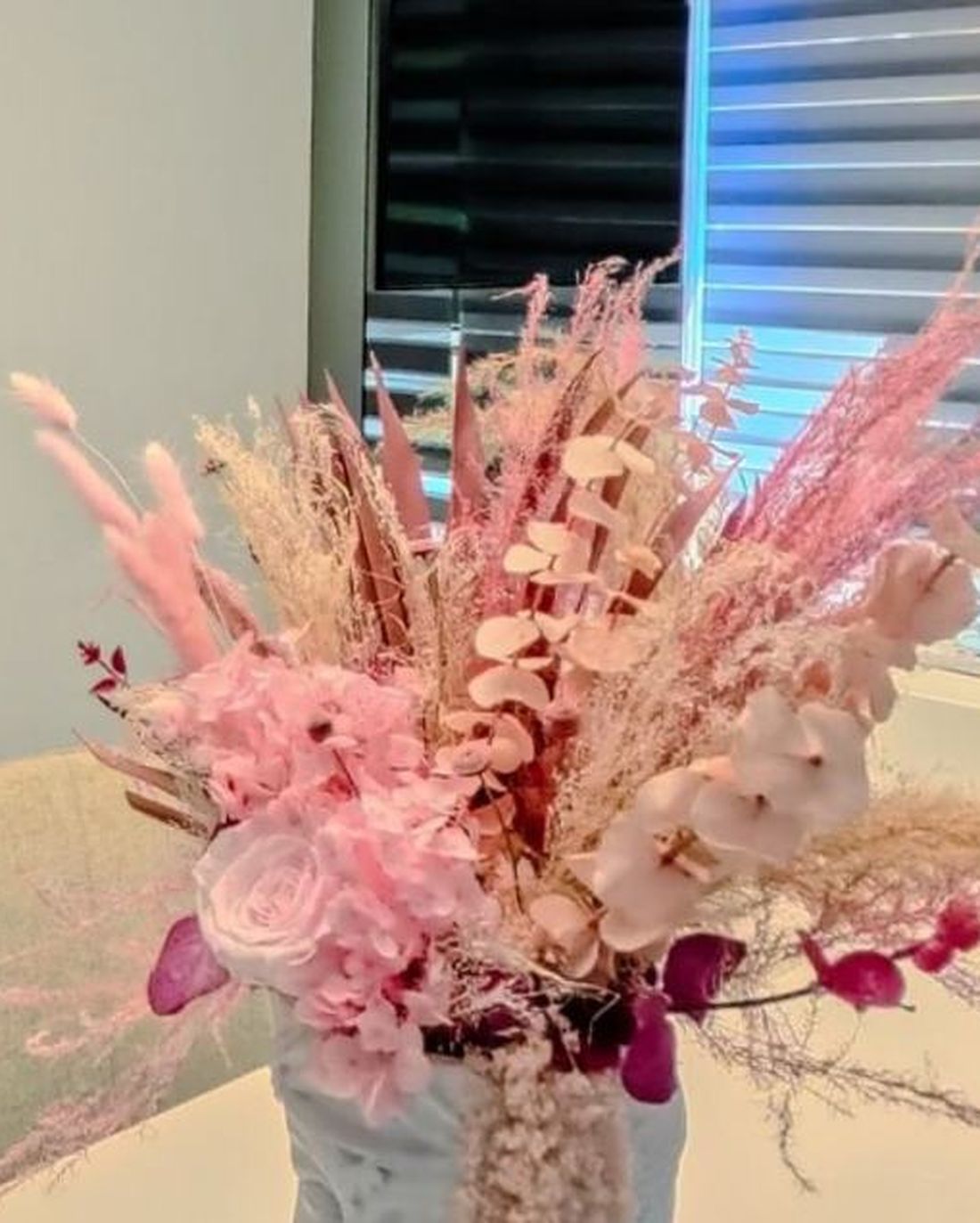 A tall arrangement of dried pink flowers on the reception counter