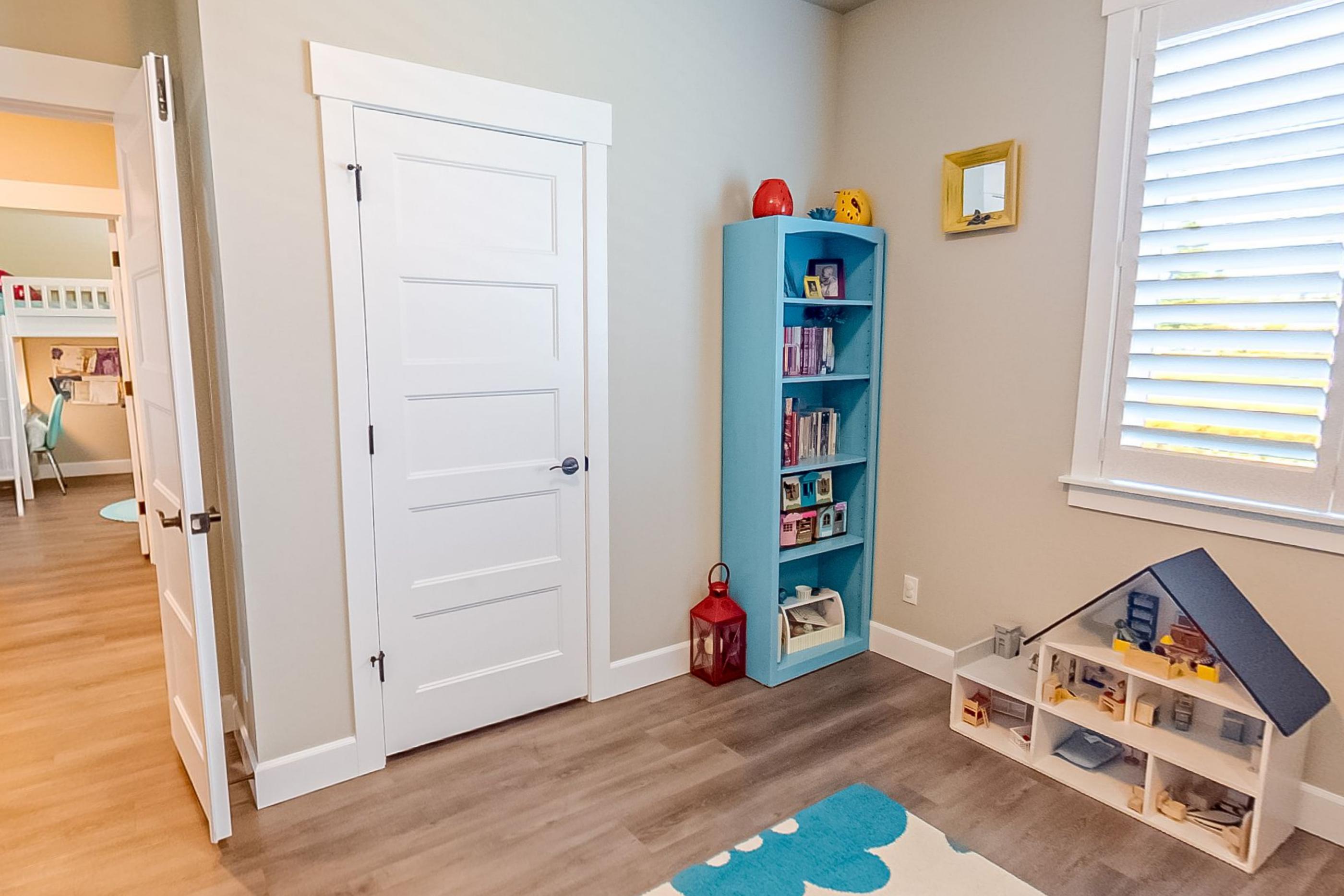 A children's room with a blue bookshelf, books and a wooden dolls' house on the floor
