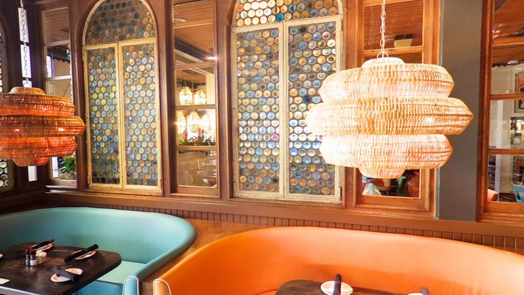 Curved orange and teal booths under a large woven chandelier