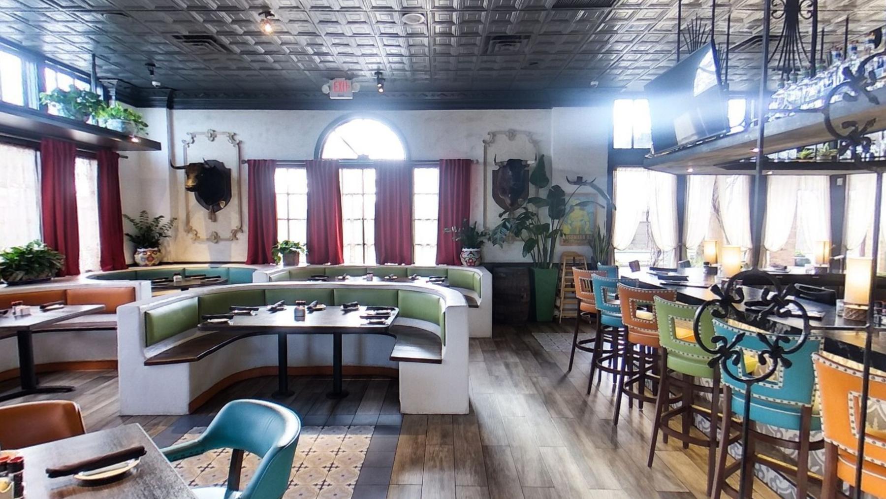 The main dining hall with a long curved banquette and the bar behind