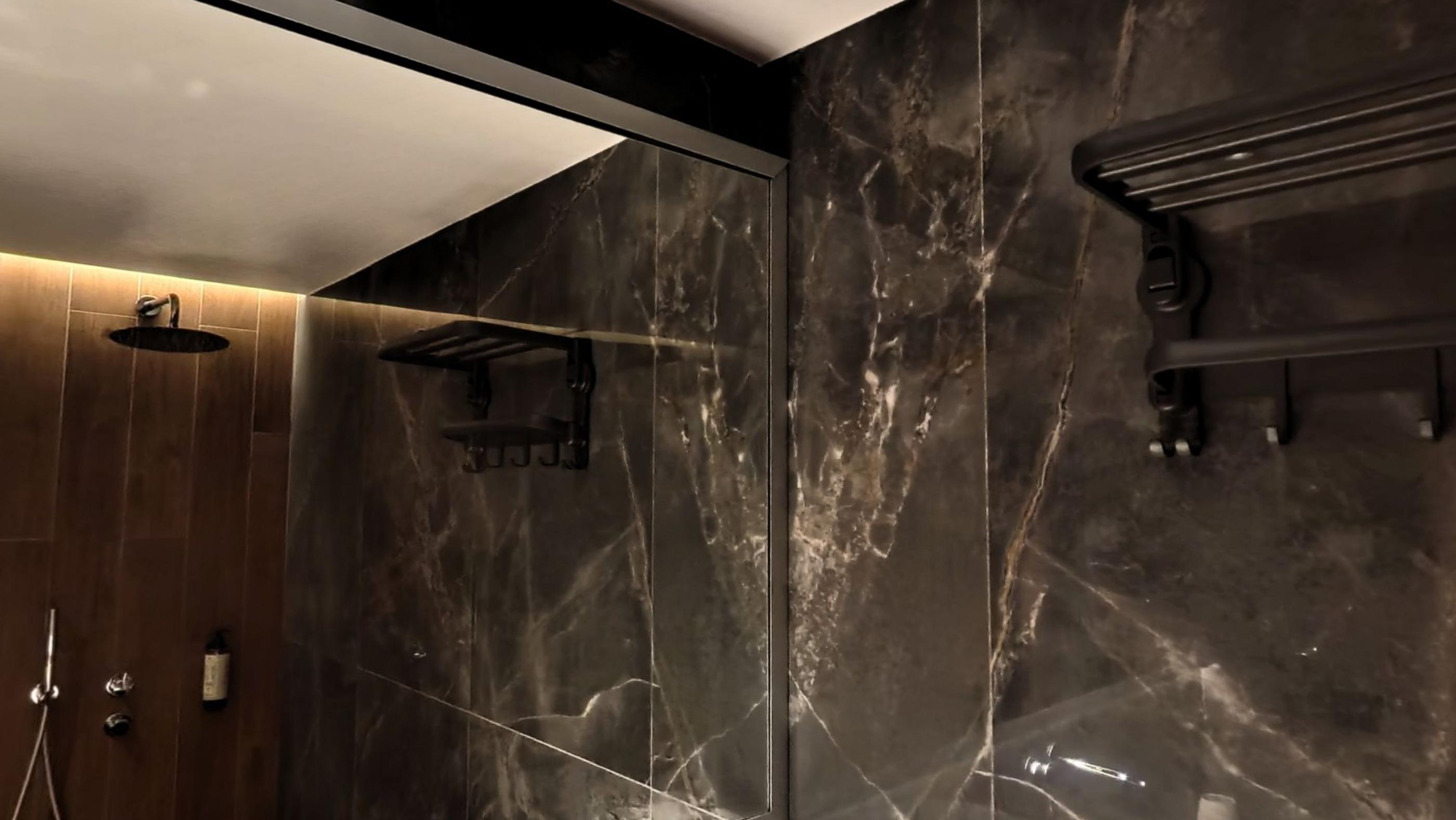 A bathroom in dark marble with a rain shower
