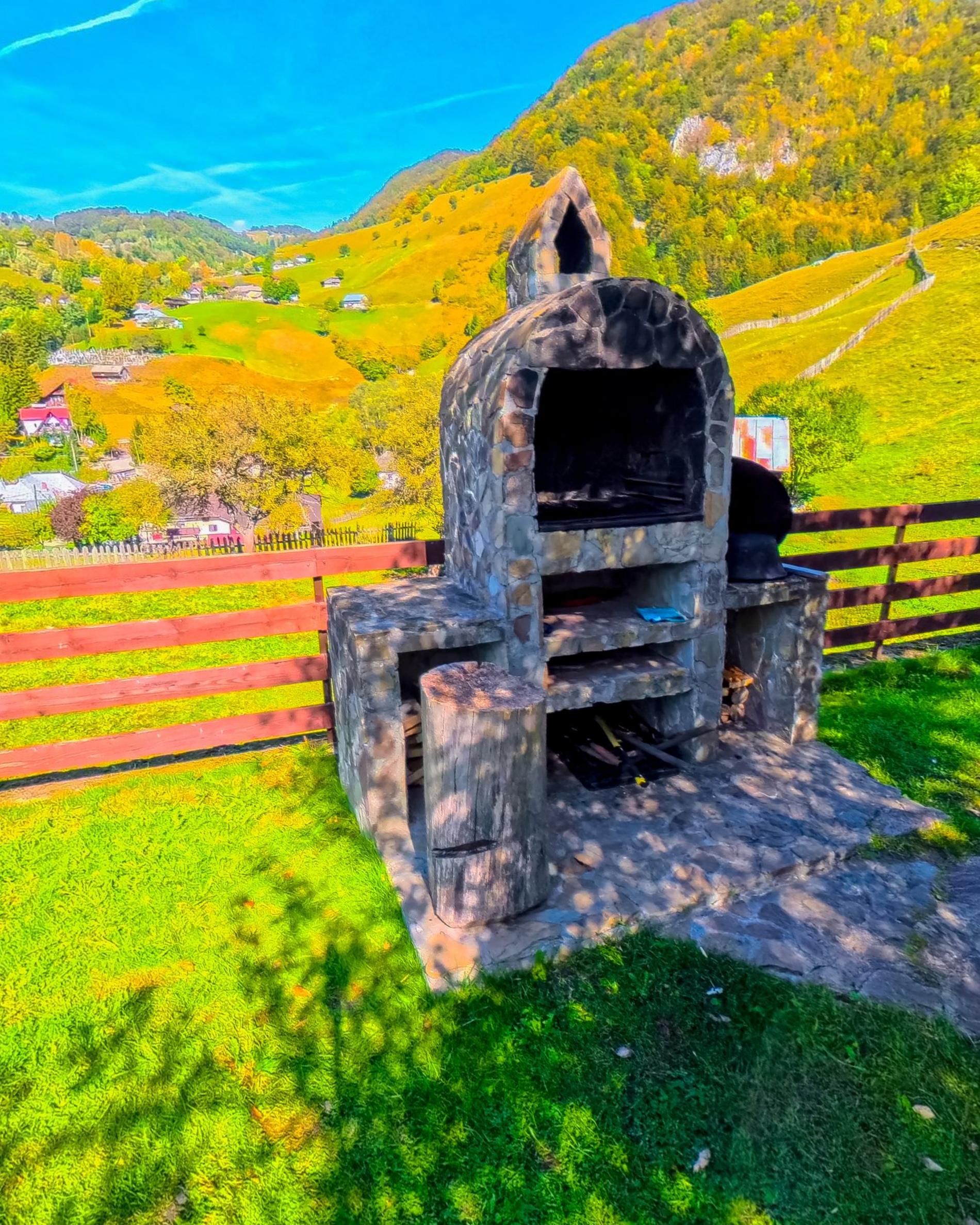 A stone grill built in the garden with the village and the hillside behind it