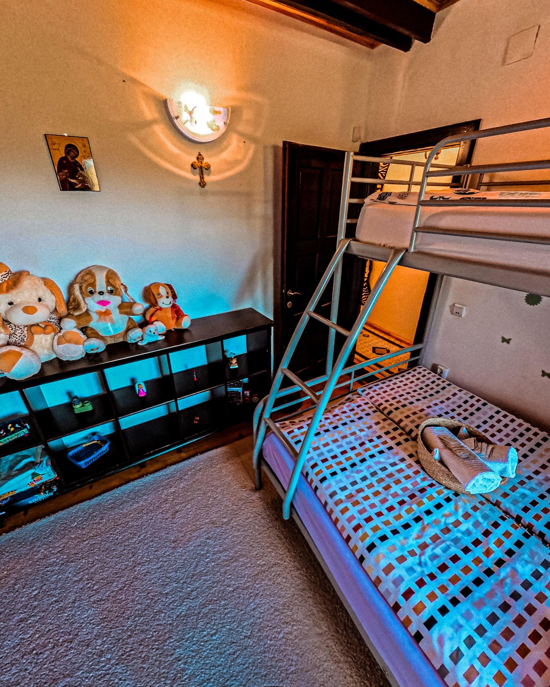The children's room with a bunk bed, soft toys lined up on a low shelf and a small icon on the wall