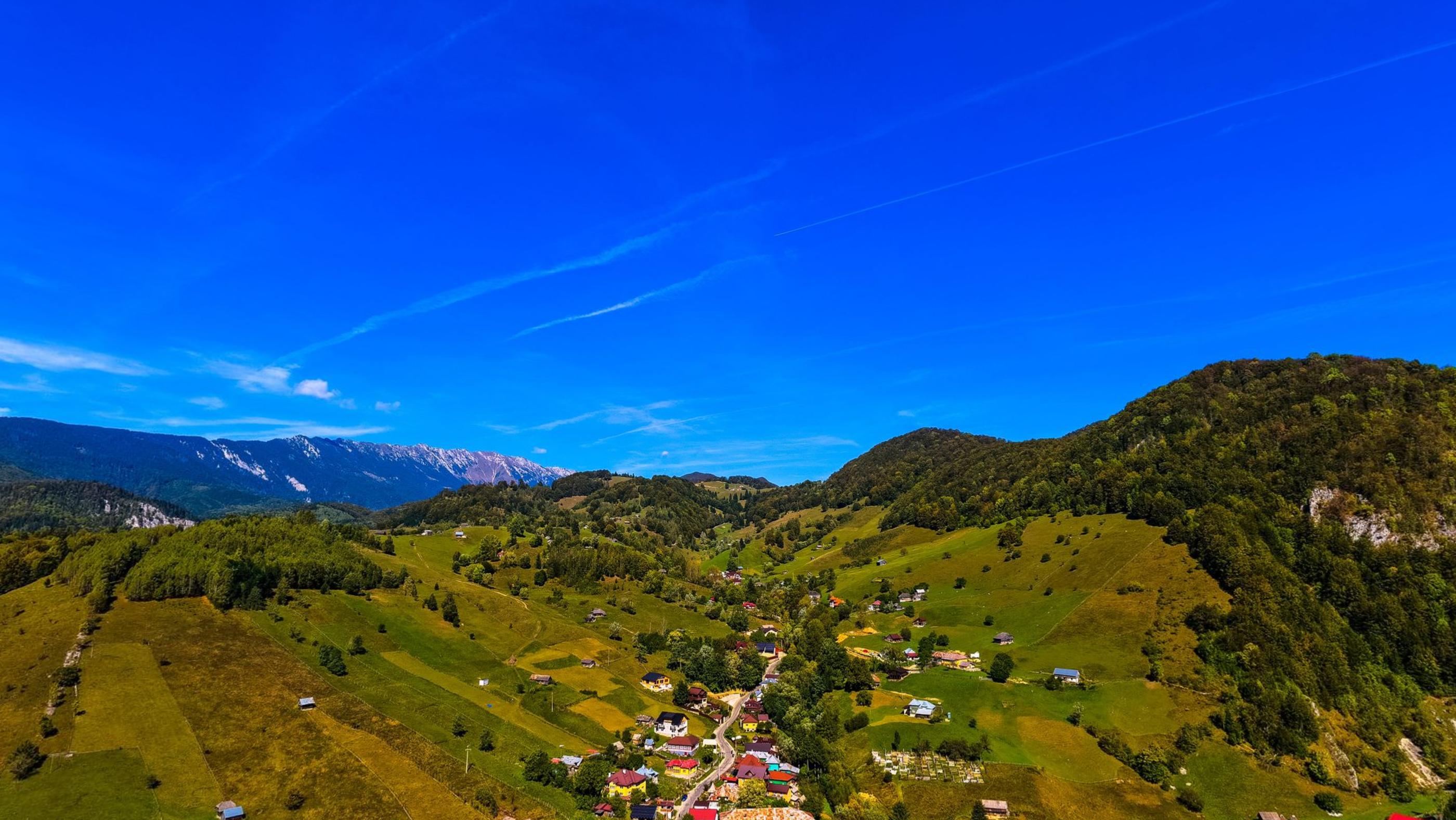 The village of Dambovicioara spread along the valley floor with wooded ridges above it