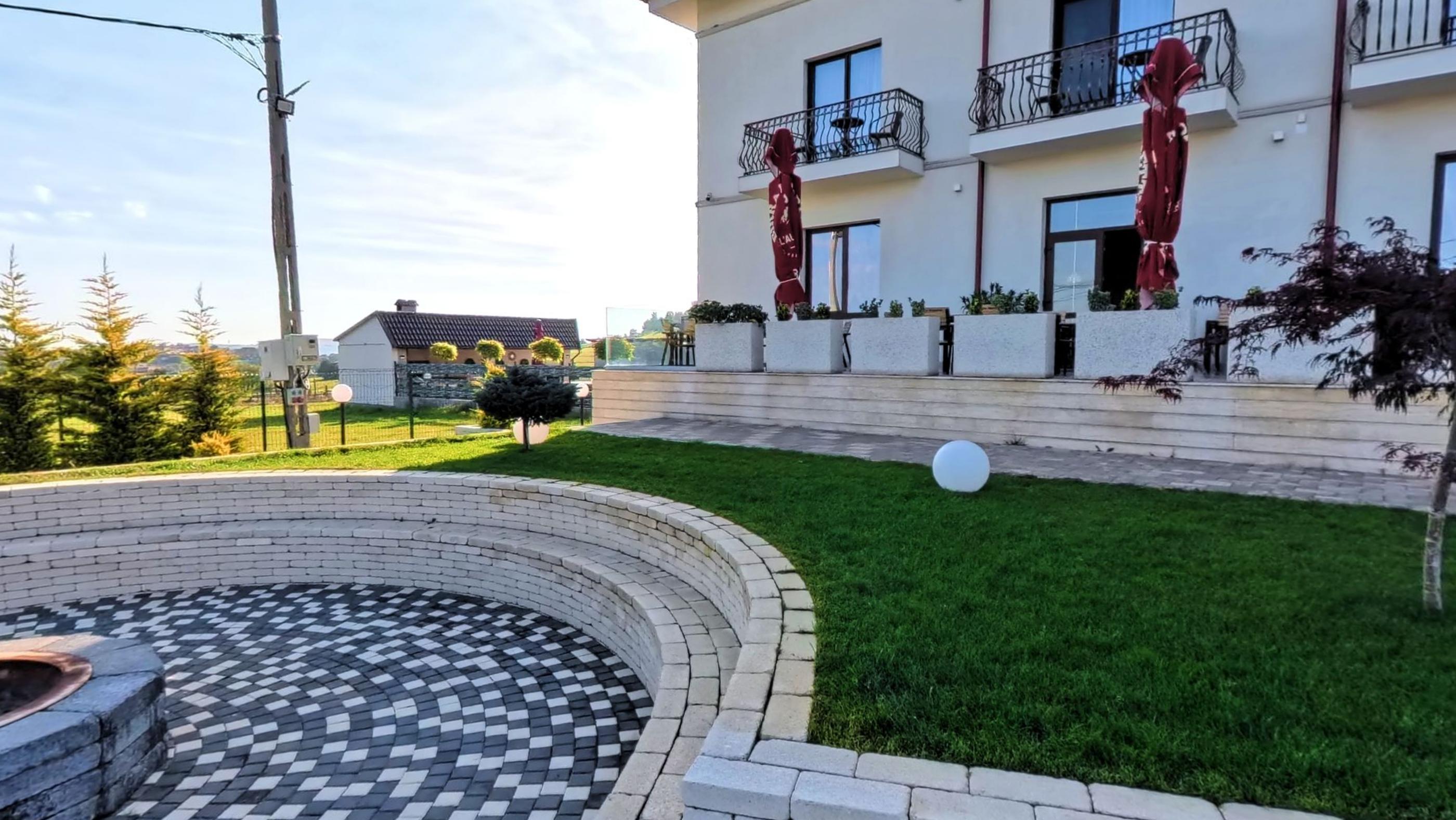 The white facade of the hotel behind a clipped lawn and stone paving