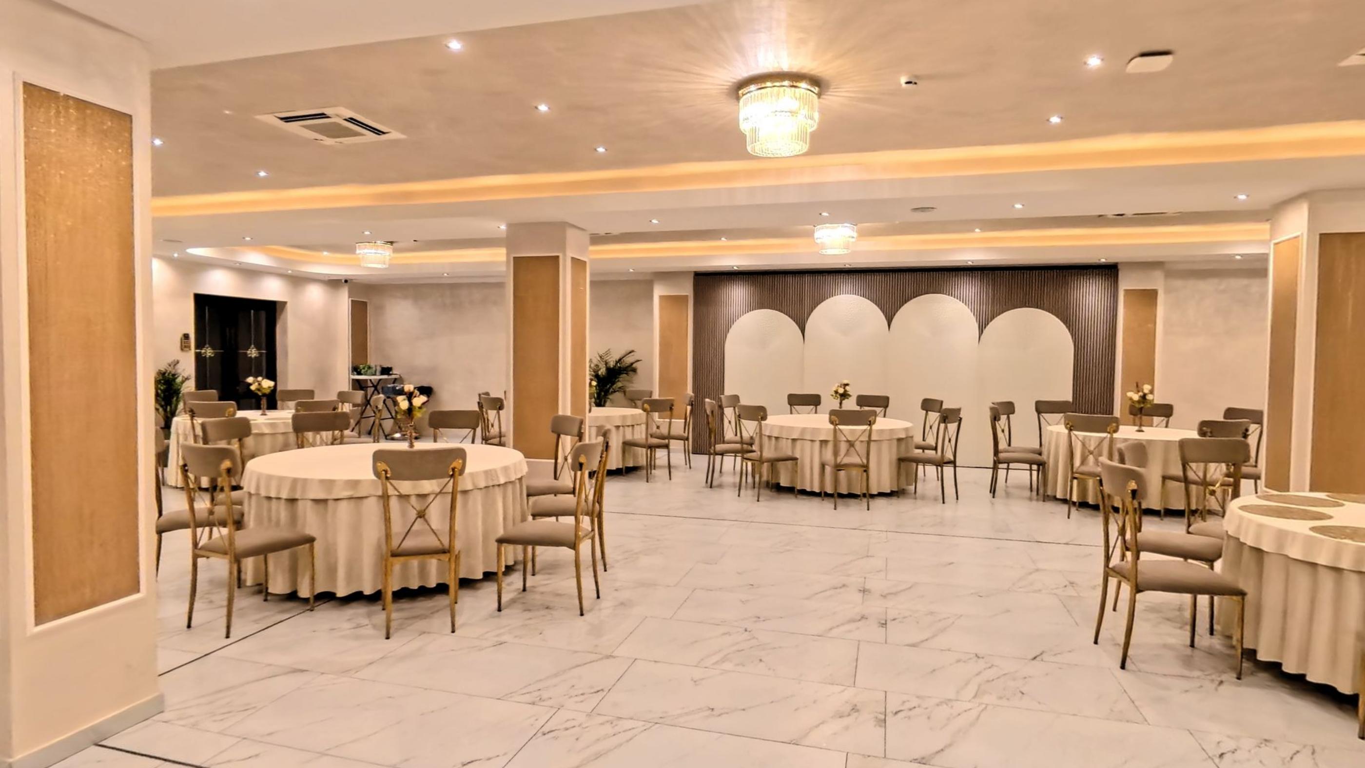 The event hall laid with round tables under arched drapery