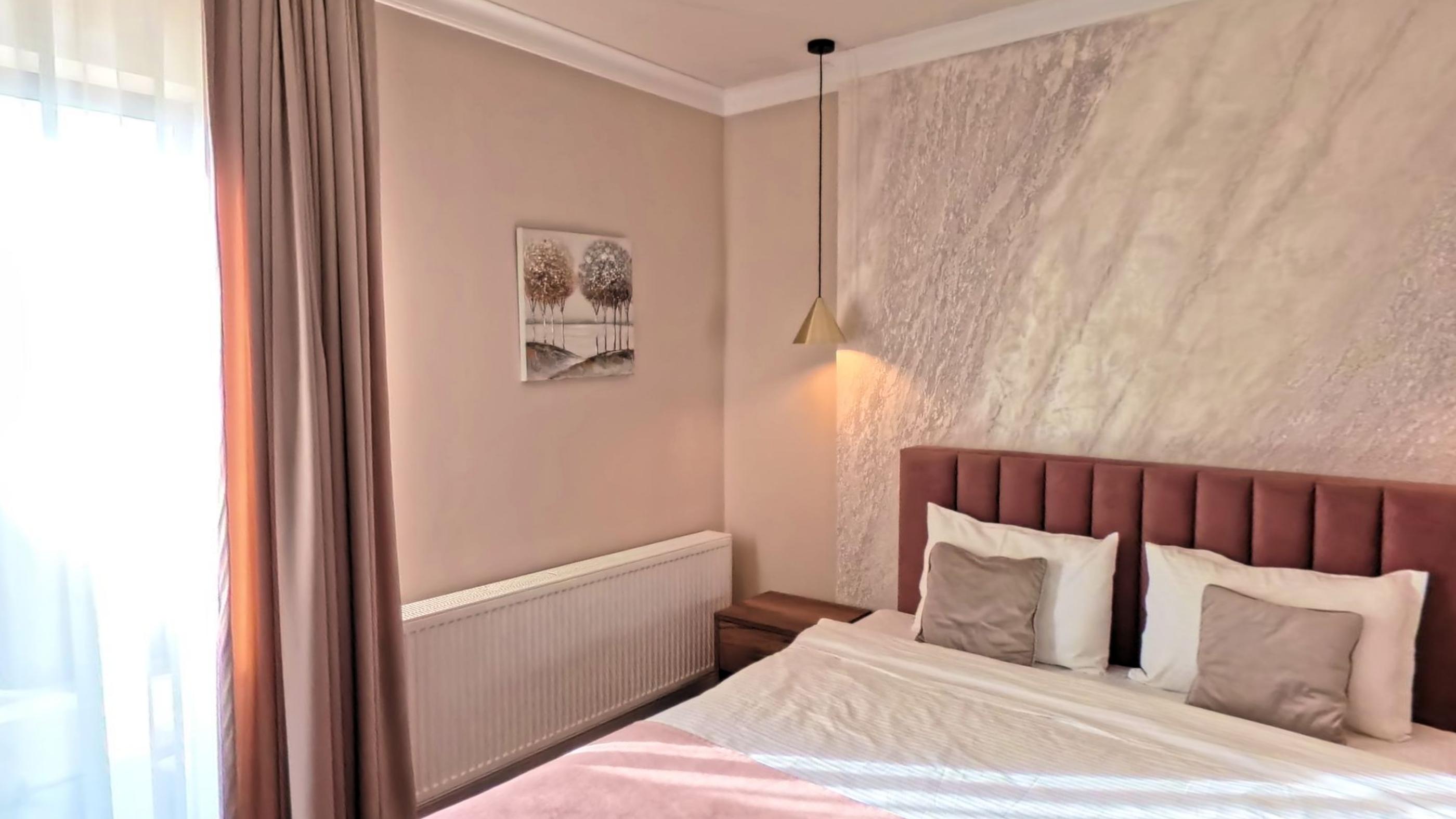 A guest room with a wide bed, warm lamps and a curtained window
