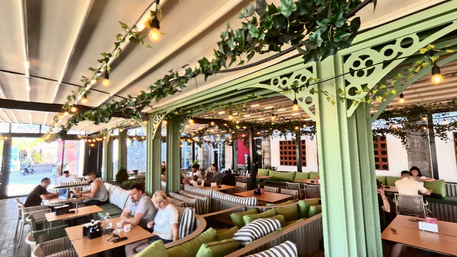 The long terrace at Marty Westside under a pitched roof, sage green columns wound with ivy