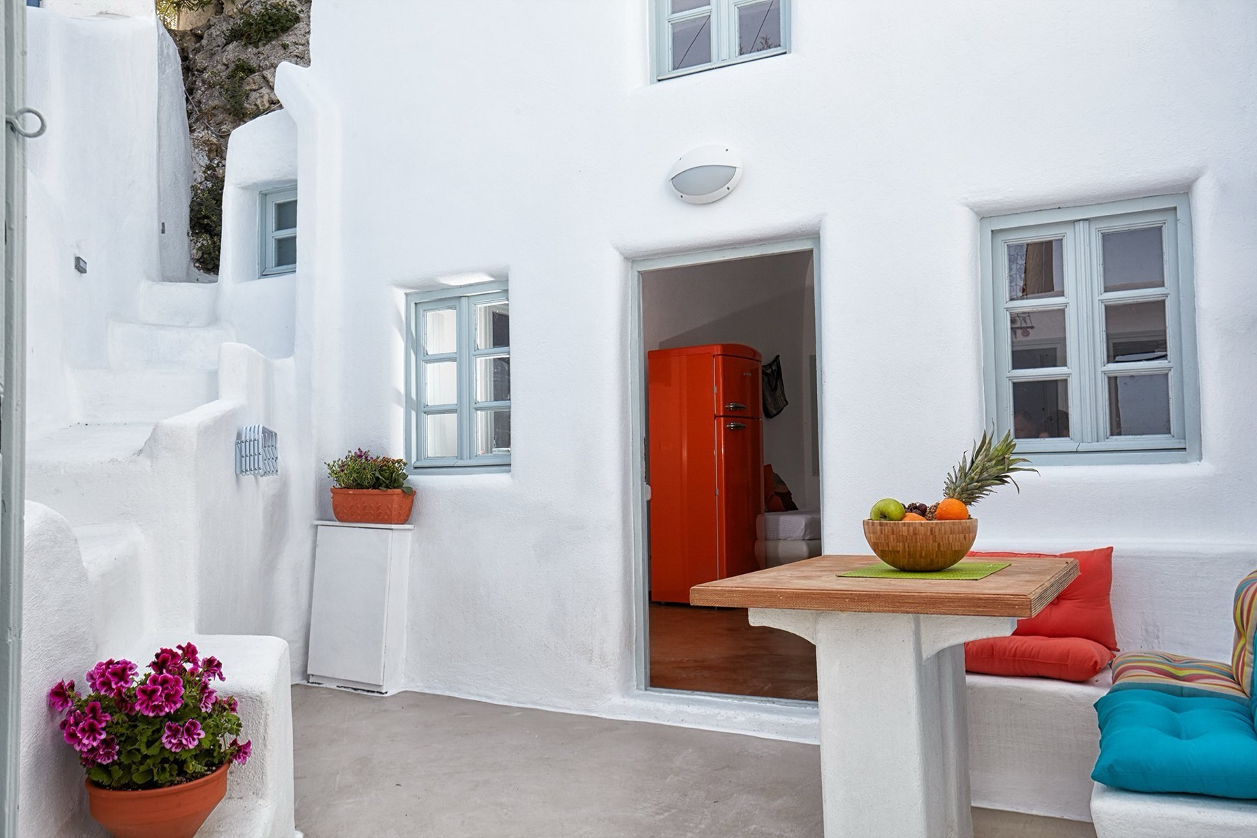 The private whitewashed courtyard with a table, geraniums and the front door open
