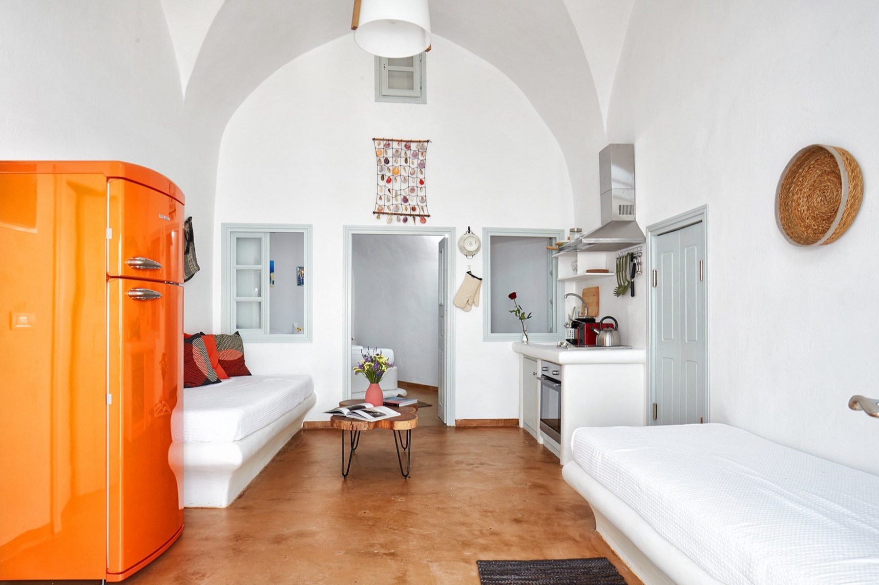The vaulted living room with terracotta floor, built-in beds and an orange fridge