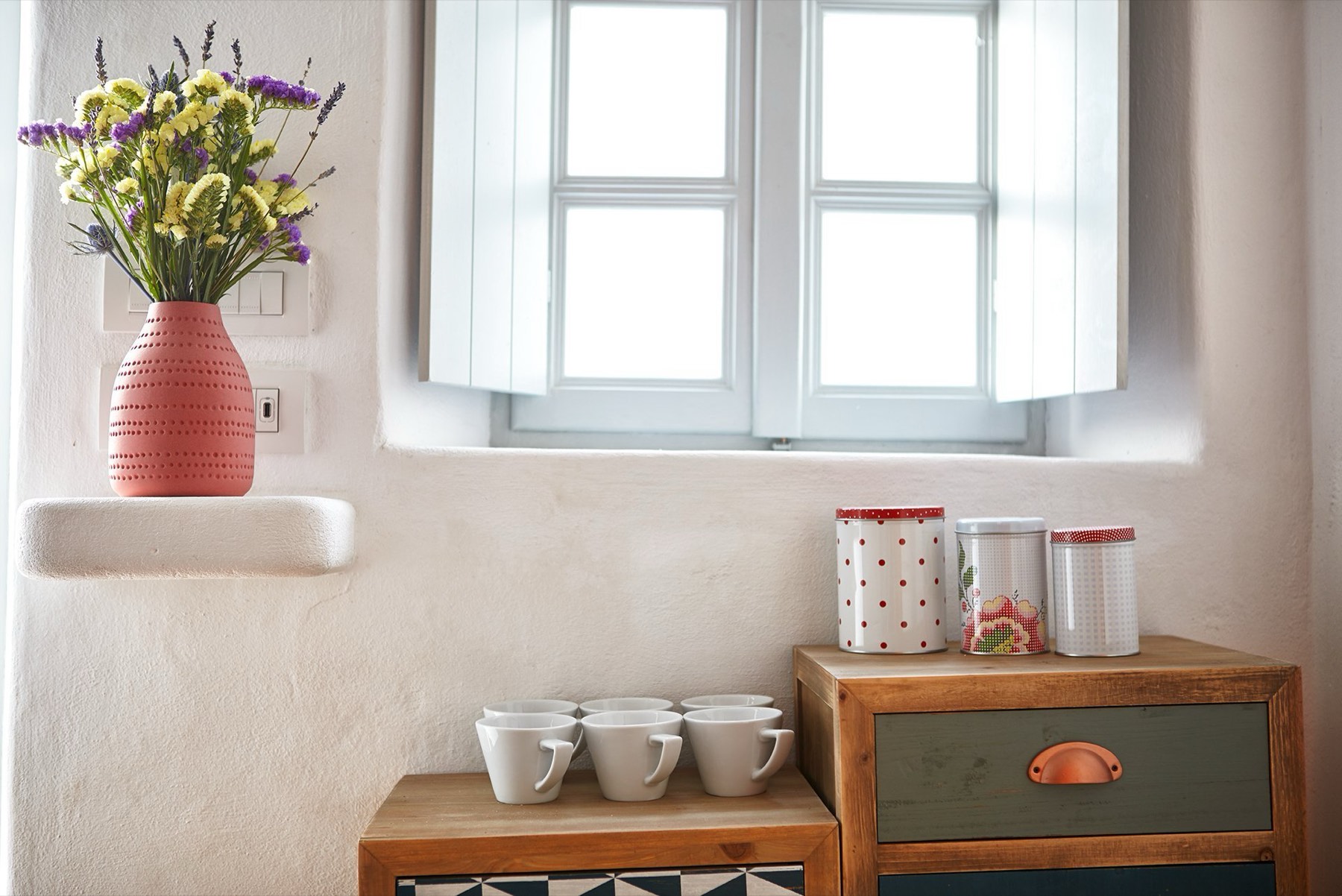 Coffee cups and dried flowers on a shuttered windowsill