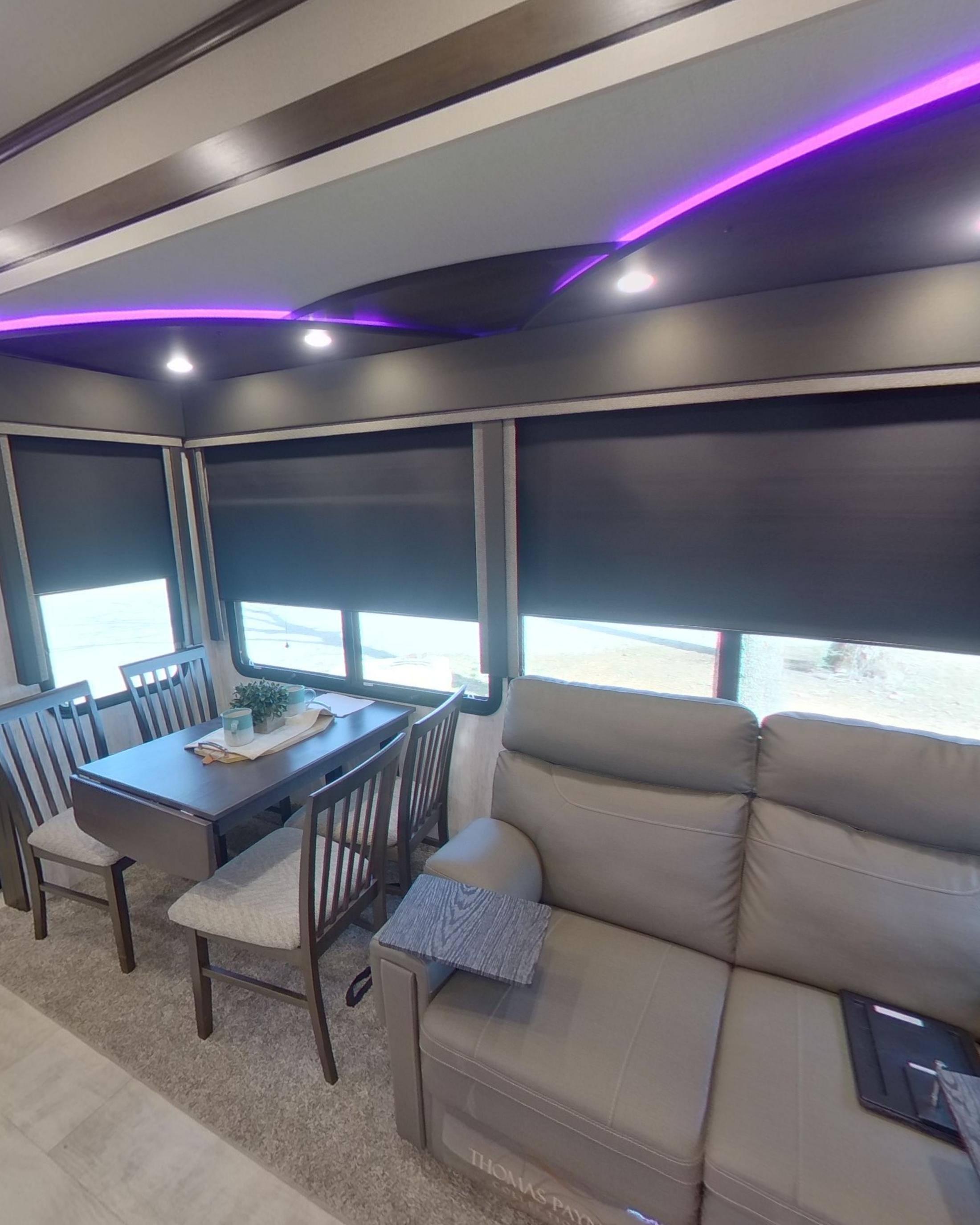 The dinette table and chairs beside the sofa with the window shades half down