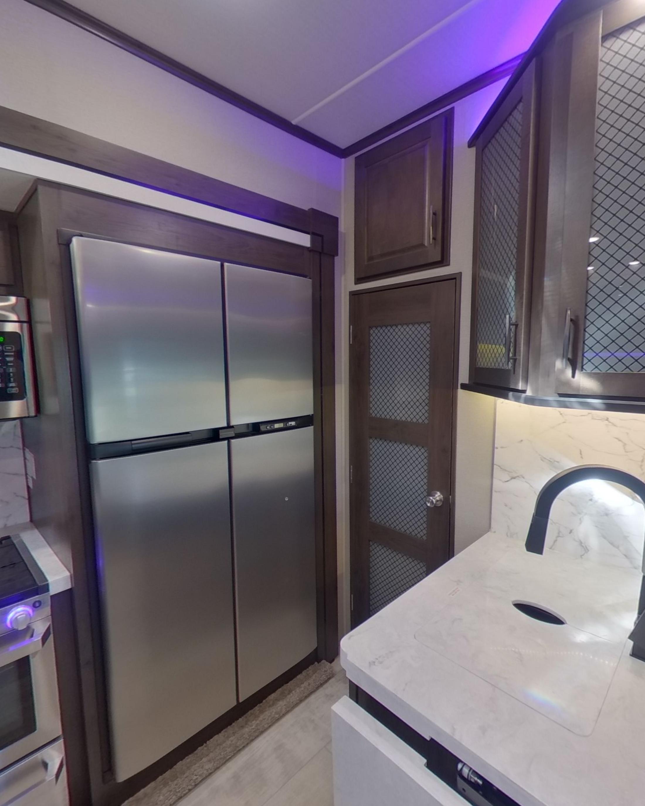 A full height stainless steel fridge and freezer beside the worktop and sink