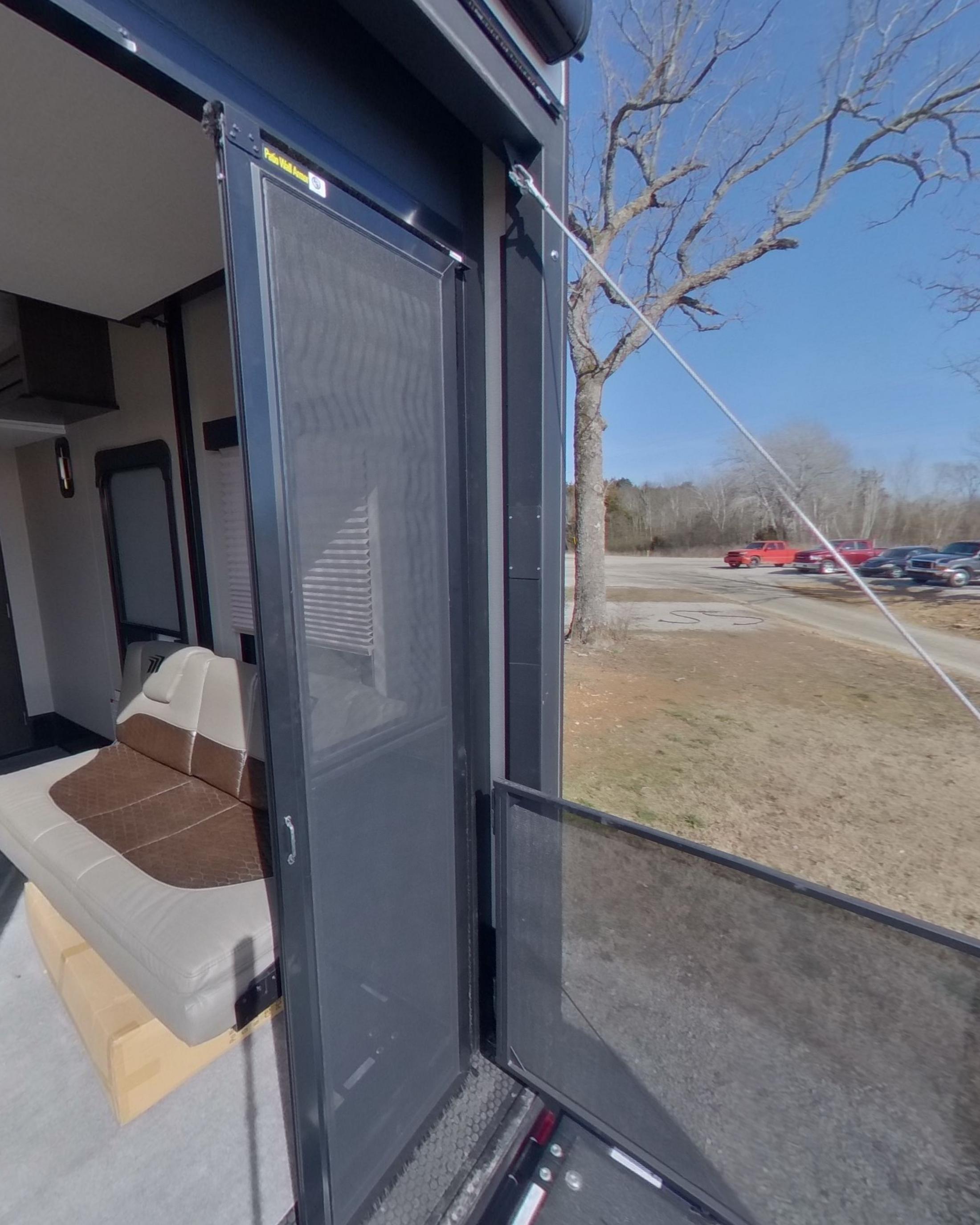 The rear ramp lowered into a patio deck with a railing and a screen door