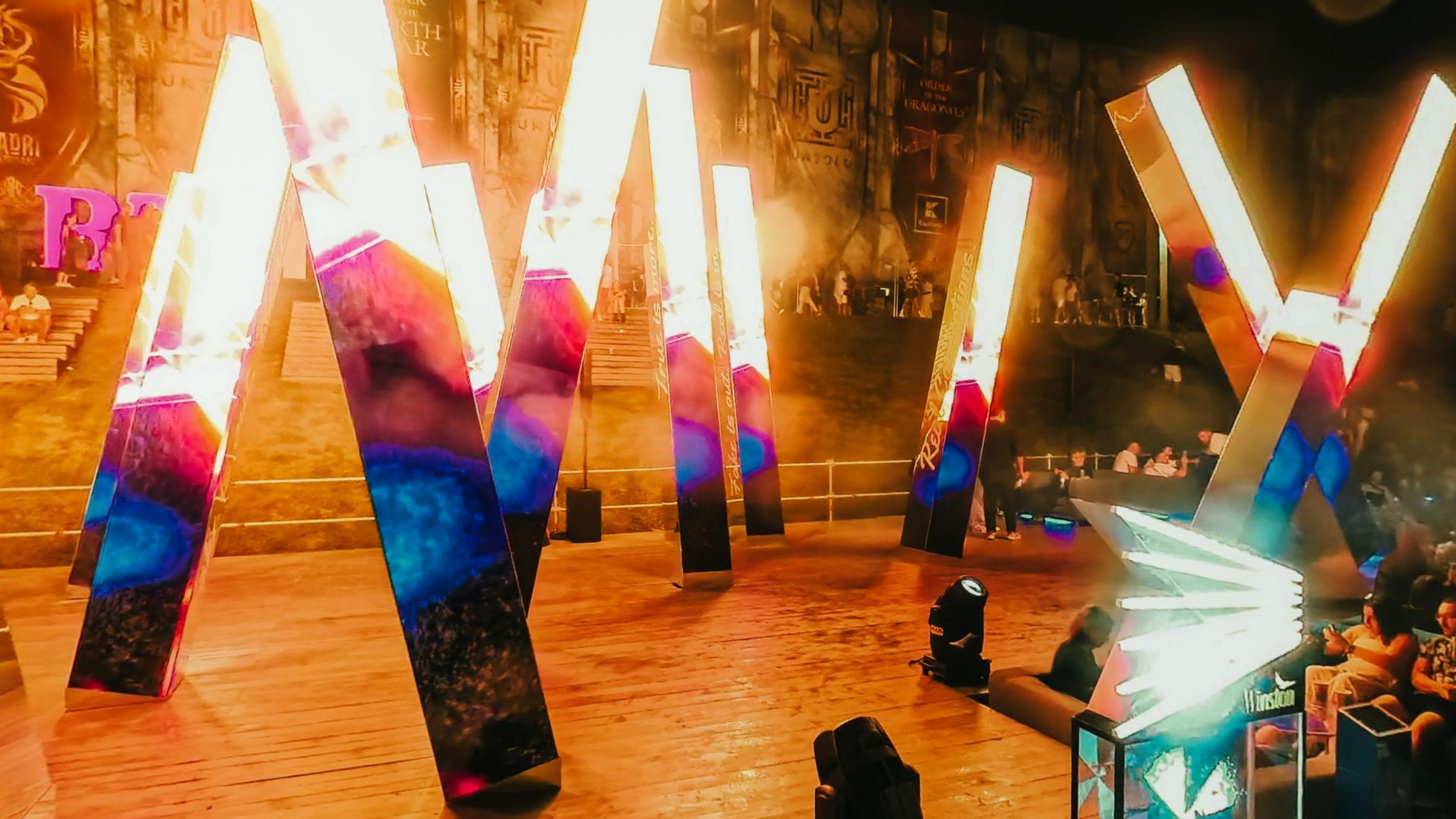 Giant illuminated letters on a stage with flame jets firing behind them